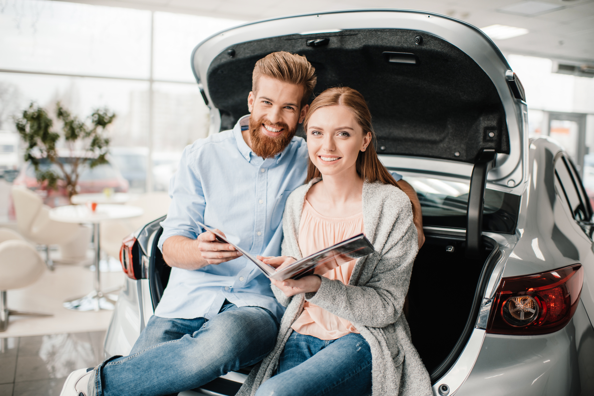 Couple Sitting on Truck of Car in Dealership with Auto Insurance in Santa Maria, CA